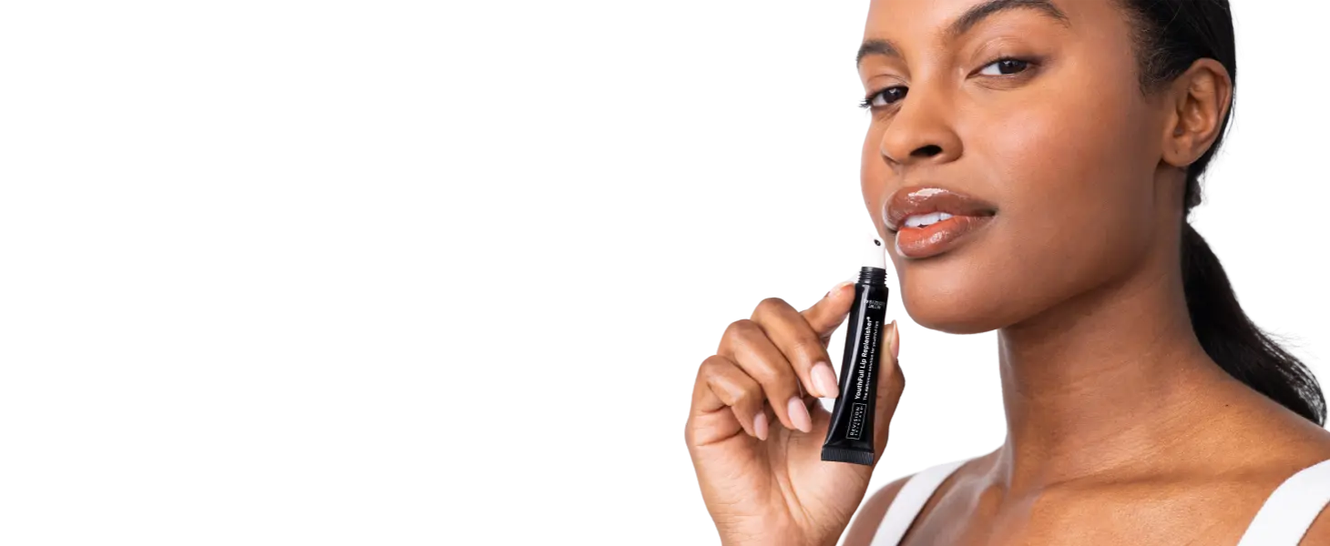 Woman applying top Revision skincare products to address signs of aging Youthful Lip Replenisher